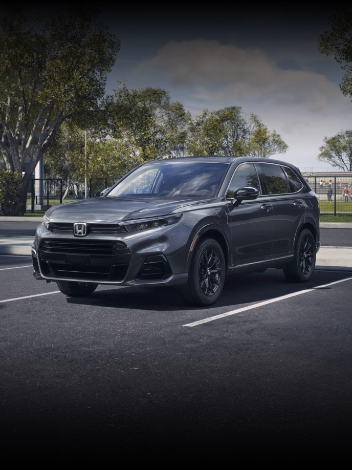 Front driver of 2026 CR-V e:FCEV in Meteorite Gray Metallic parked in a sports complex parking lot.