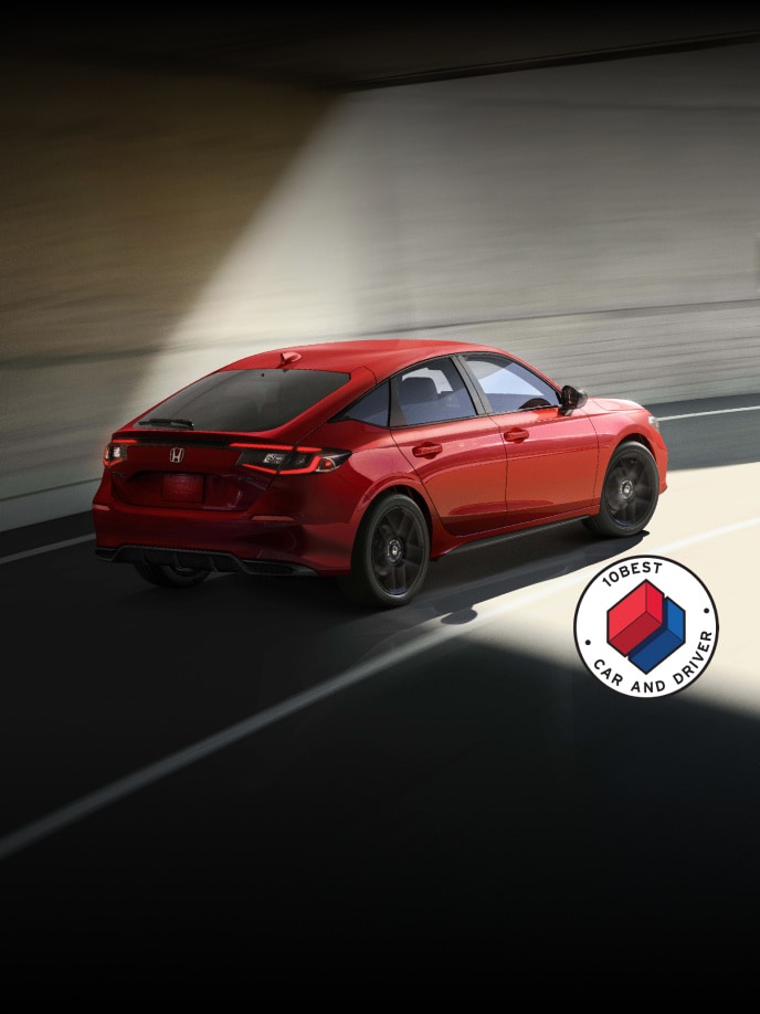 2026 Honda Civic Hatchback Sport in Rallye Red rear view Driving through a tunnel with overlapping Car and Driver 10Best logo (Compact Hatchback).