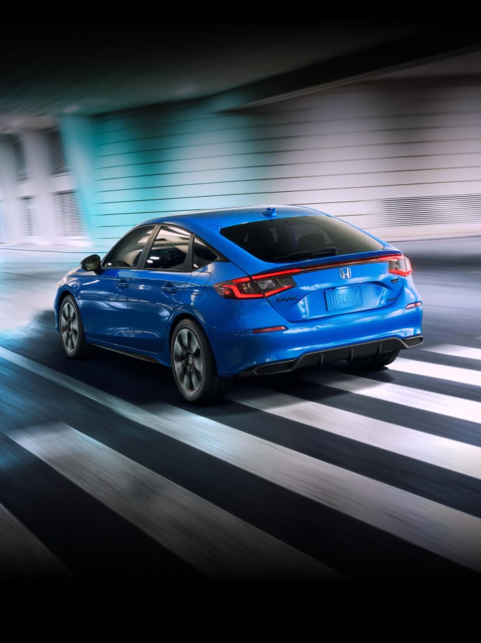 2027 Honda Civic Hatchback Sport Touring Hybrid in Boost Blue Pearl back driving through a tunnel (Compact Hatchback).