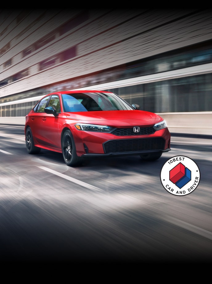 2027 Honda Civic Sedan Civic Sedan Sport in Rallye Red front view driving on a street with overlapping Car and Driver 10Best logo (Compact Sedan).