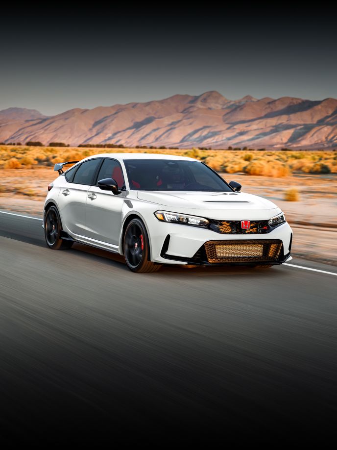 Vista frontal del Honda Civic Type R 2025 en Championship White conduciendo por un camino con fondo desértico