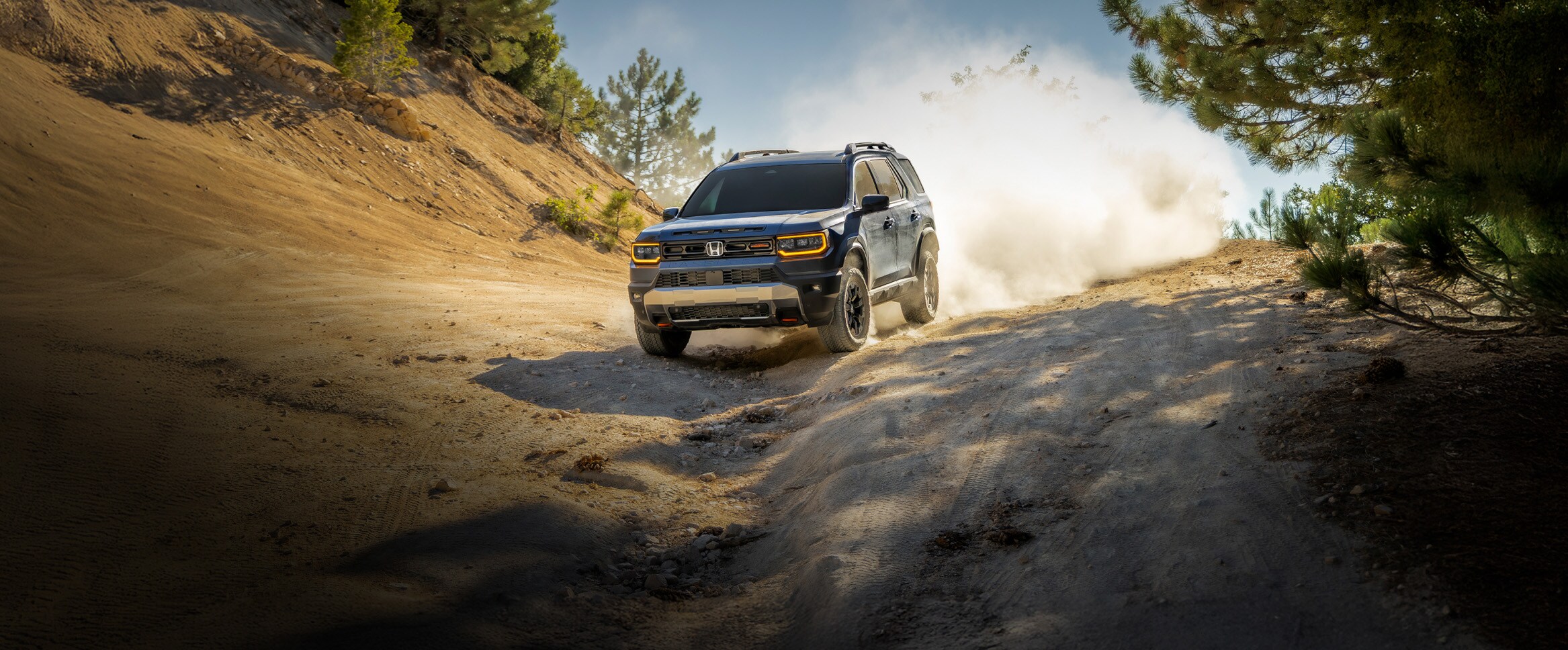 2027 Honda Passport TrailSport Elite in Smoke Blue Pearl profile driving on a dusty off-road trail (Mid-Size SUV).