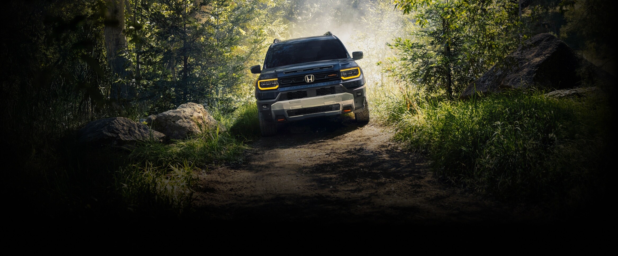 2027 Honda Passport TrailSport Elite in Smoke Blue Pearl in a front view, driving on an off-road trail (Mid-Size SUV).