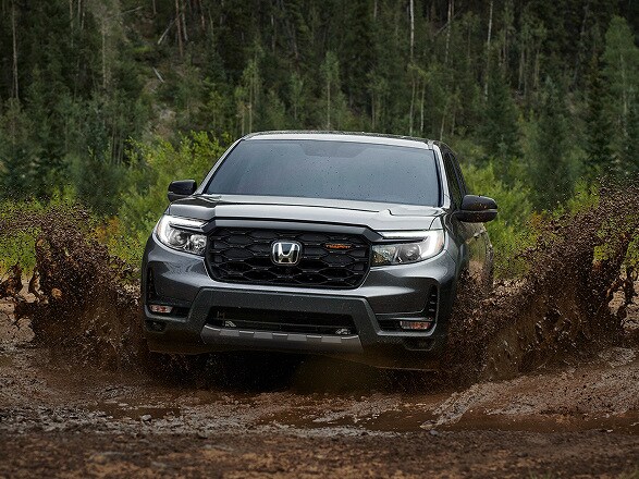 2026 Honda Ridgeline in Modern Steel Metallic front driving through mud in a forest (Midsize Pickup Truck).
