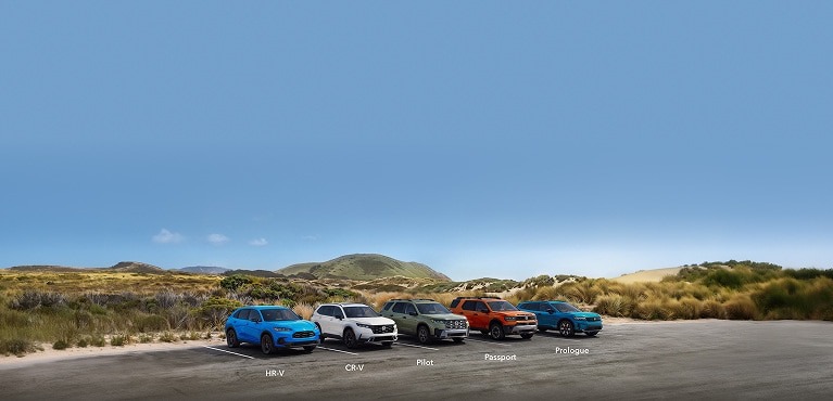 2027 Honda SUVs profile parked in a coastal lot with grassy hills (Mid-Size SUV).