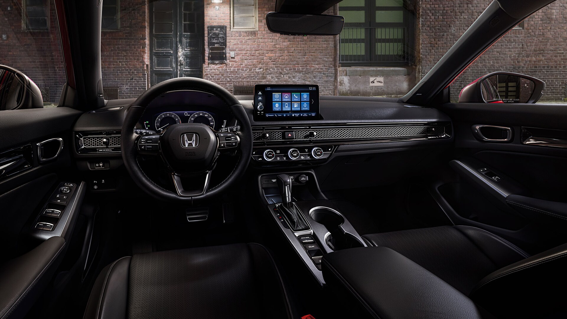 Interior view of the 2022 Honda Civic Sport Touring Hatchback with Black Leather, with a brick building visible through the windshield.
