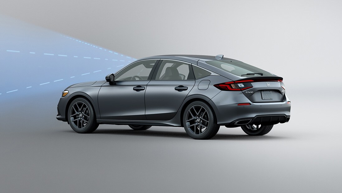 Rear driver-side view of the 2022 Honda Civic Sport Touring Hatchback in Sonic Gray Pearl with illustrated lines demonstrating Honda Sensing® feature.
