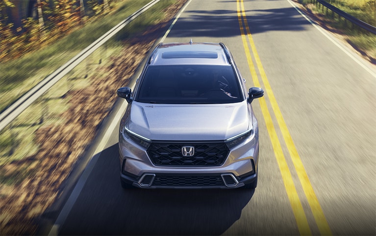 2026 Honda CR-V Sport Touring front view of vehicle driving on a curved road crossing a lake.