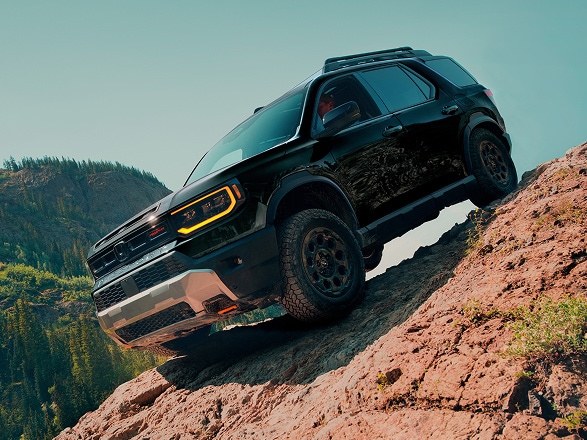 2026 Honda Passport Trailsport Elite in Crystal Black Pearl  front off-roading up a steep rocky mountain (Mid-Size SUV).