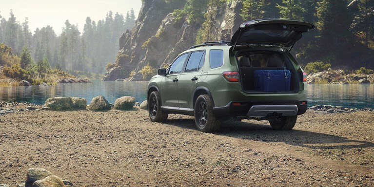 2026 Honda Pilot TrailSport shown in Ash Green Metallic with Honda Genuine Accessories in the lake