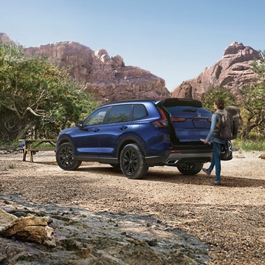 2027 Honda CR-V Sport Touring Hybrid in Canyon River Blue Metallic parked in a mountain landscape (Compact Crossover SUV).