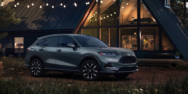 2027 Honda HR-V EX-L in Nordic Forest Pearl three quarter view parked in front of a cabin (Subcompact Crossover SUV).