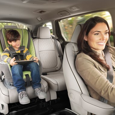 Honda Odyssey family van showing child in a car seat in the second row with a driver in the front (Minivan).