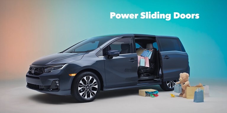 2027 Honda Odyssey Elite in Smoke Blue Pearl profile studio with shopping bags and power sliding doors (Minivan).