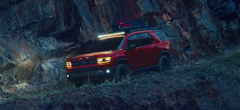 2027 Honda Passport TrailSport Elite in Radiant Red Metallic II front on a steep and rugged rocky mountain (Mid-Size SUV).