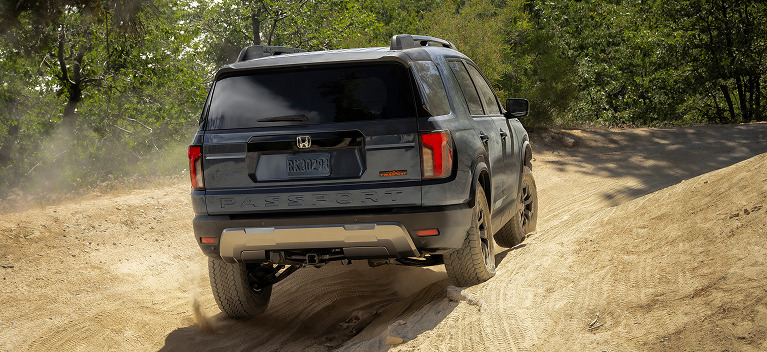 2027 Honda Passport TrailSport Elite in Smoke Blue Pearl back driving on a rugged dirt trail (Mid-Size SUV).