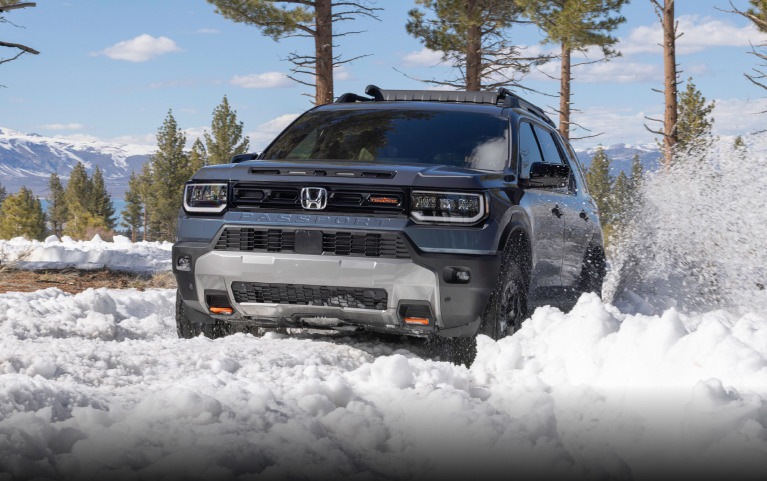 2027 Honda Passport TrailSport Elite in Smoke Blue Pearl front driving through deep snow in the mountains (Mid-Size SUV). 2027 Honda Passport TrailSport Elite in Smoke Blue Pearl front driving through deep snow in the mountains (Mid-Size SUV).