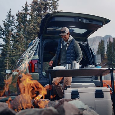 2027 Honda Passport TrailSport Elite in Ash Green Metallic back parked at a campsite with a campfire (Mid-Size SUV).