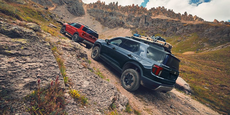 2027 Honda Passport TrailSport Elite in Smoke Blue Pearl back climbing a steep rocky mountain trail (Mid-Size SUV).