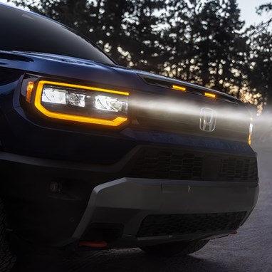 2027 Honda Passport TrailSport Elite in Smoke Blue Pearl front outdoors at dusk with glowing headlights (Mid-Size SUV).