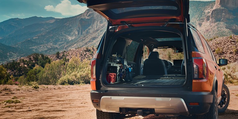 2027 Honda Passport TrailSport Elite in Sunset Orange back parked on a scenic desert mountain trail (Mid-Size SUV).