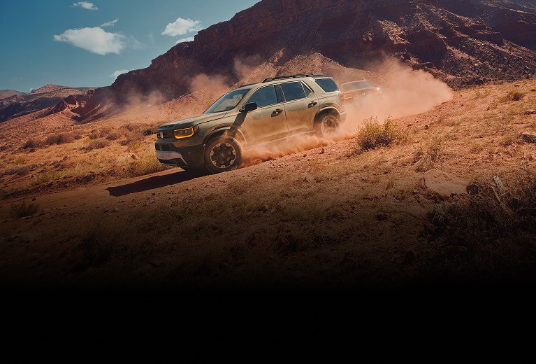 2027 Honda Passport TrailSport Elite in Ash Green Metallic profile driving on a dusty desert trail (Mid-Size SUV). 2027 Honda Passport TrailSport Elite in Ash Green Metallic profile driving on a dusty desert trail (Mid-Size SUV).