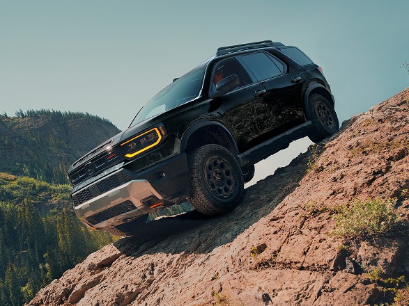 2027 Honda Passport TrailSport Elite in Crystal Black Pearl front climbing a steep rocky hill (Mid-Size SUV).