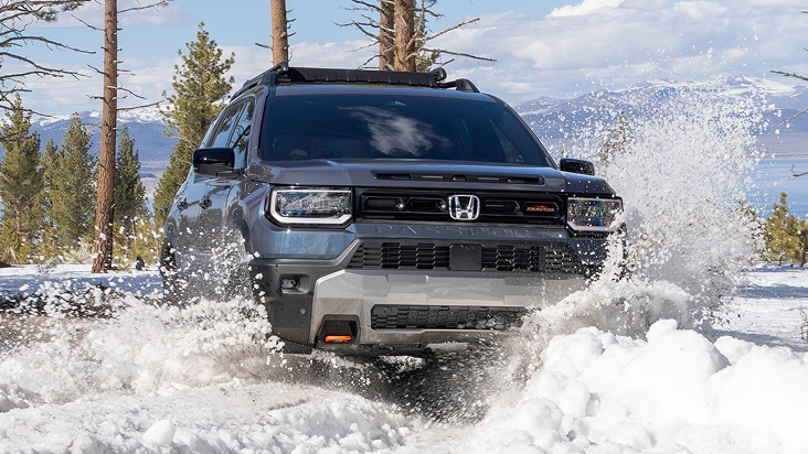 2027 Honda Passport TrailSport Elite in Smoke Blue Pearl front driving through deep snow in a forest (Mid-Size SUV). 2027 Honda Passport TrailSport Elite in Smoke Blue Pearl front driving through deep snow in a forest (Mid-Size SUV).