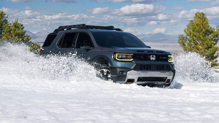 2027 Honda Passport TrailSport Elite in Smoke Blue Pearl front driving through deep snow in a forest (Mid-Size SUV).