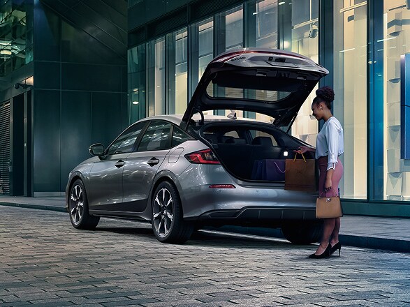 2027 Honda Civic Hatchback Sport Touring Hybrid in Solar Silver Metallic back parked on a city street with the hatch open (Compact Hatchback).